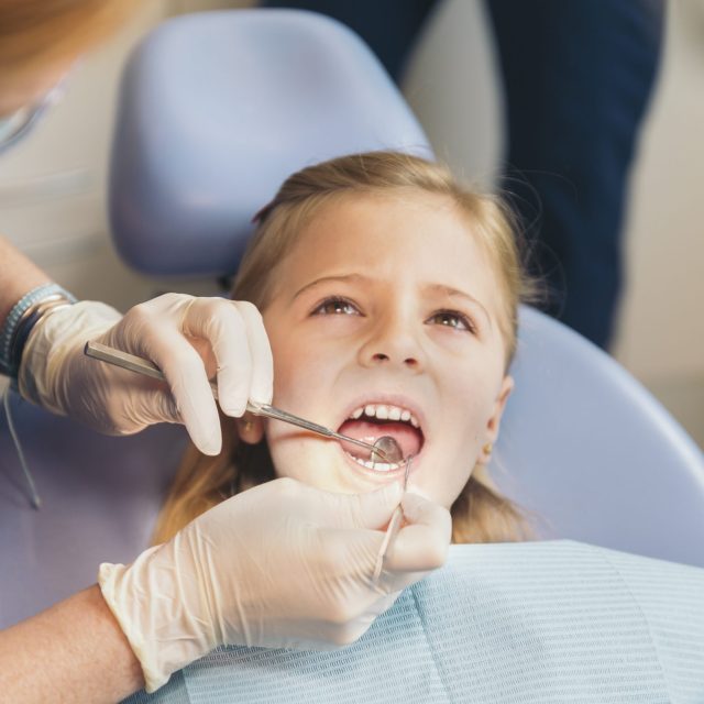 Dentists with a patient during a dental intervention to girl. Dentist  Concept